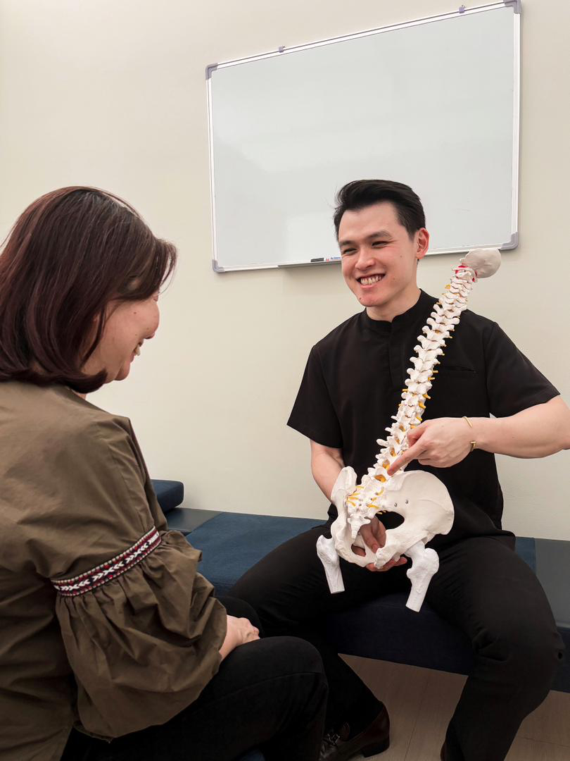Chiropractor smiling with a spine model during a consultation